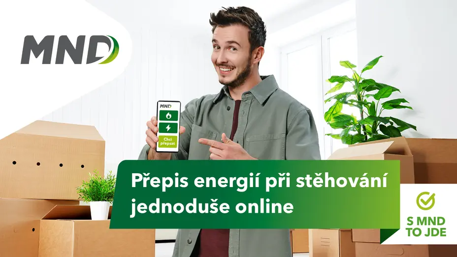 Muž stojící v místnosti plné krabic při stěhování ukazuje na svůj telefon, který zobrazuje web MND pro online přepis energií; vedle je logo MND a nápis „Přepis energií při stěhování jednoduše online“.